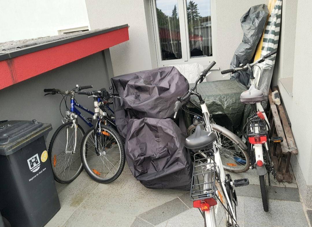 Überdachter Außenbereich mit Fahrrädern und Abstellmöglichkeiten für diverse Gegenstände.