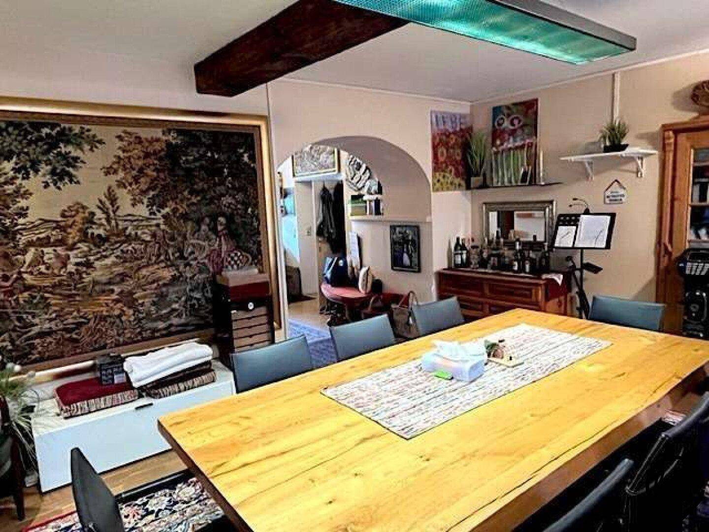 Großer Essbereich mit Holztisch, modernen Stühlen und dekorativen Wandteppichen.