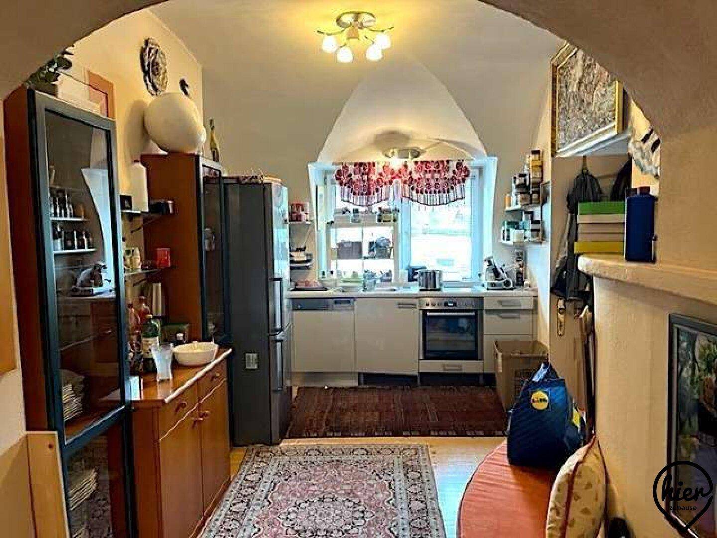 Funktionale Küche mit Einbauschränken, Geräten und einem Fenster mit Blick nach draußen.