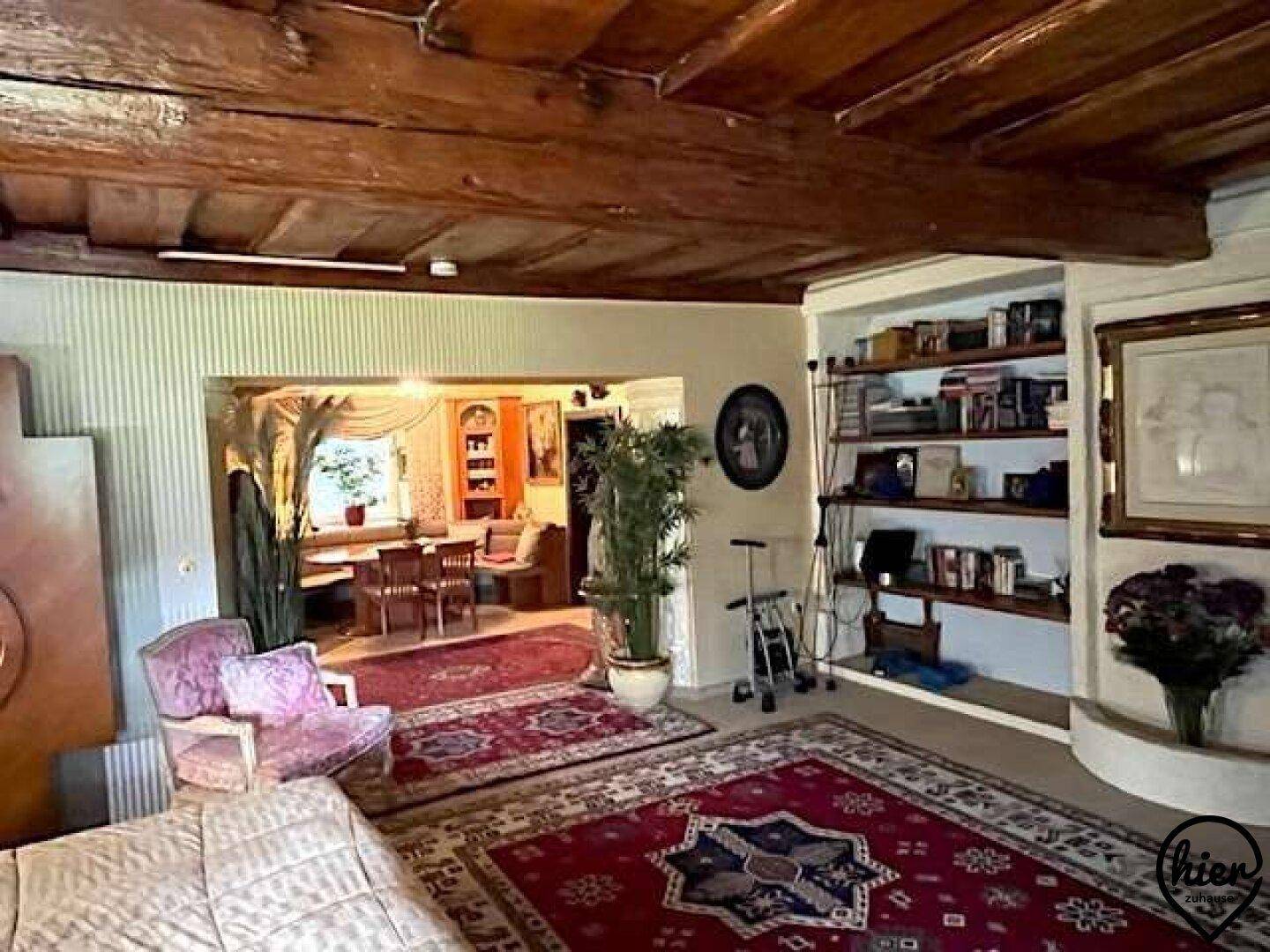 Geräumiges Wohnzimmer mit rustikalen Holzbalken, eingebauten Bücherregalen und traditionellen Teppichen.