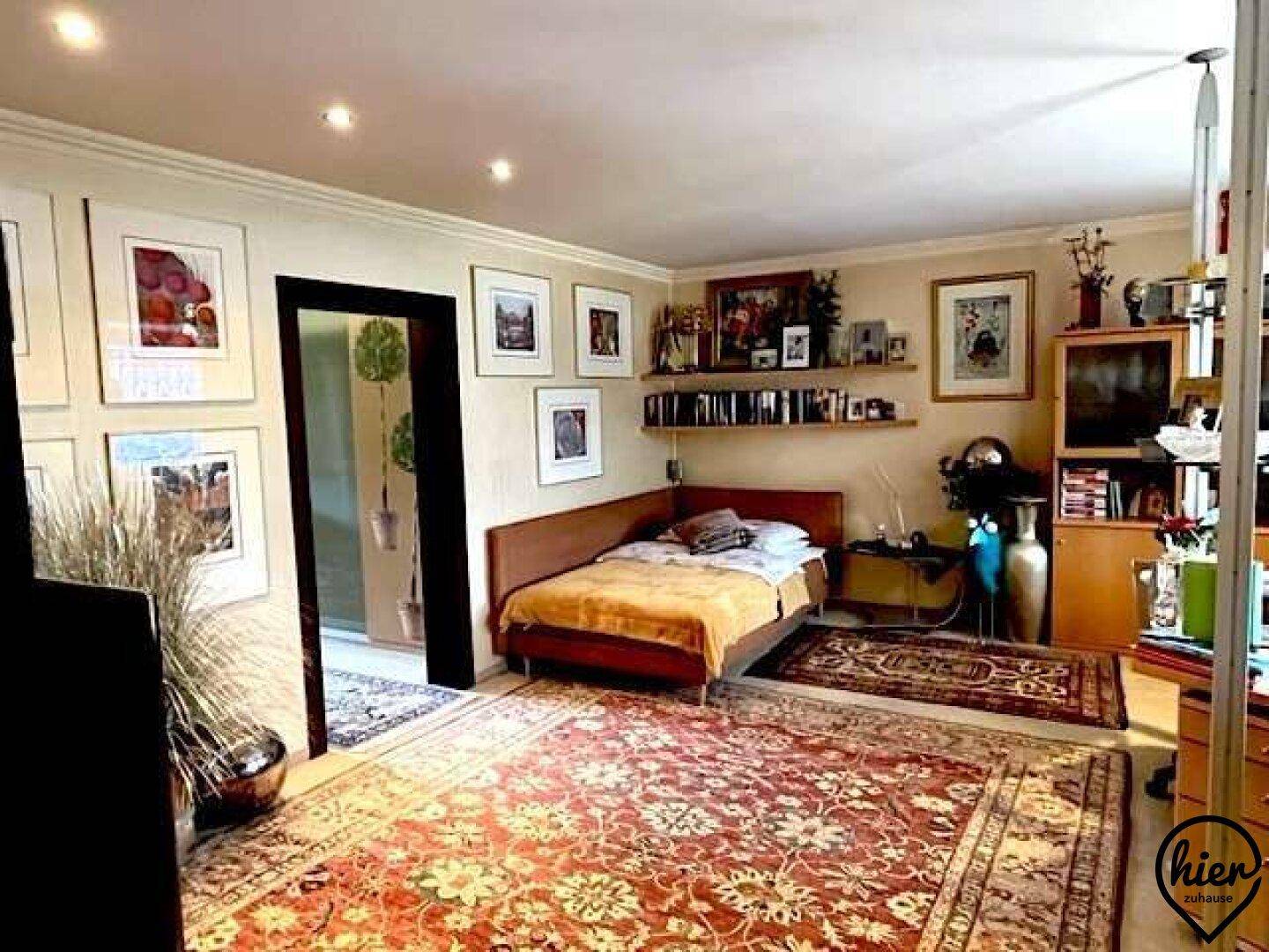 Gemütliches Schlafzimmer mit Einzelbett, Teppichboden und eingebauten Regalen für Bücher und Dekoration.