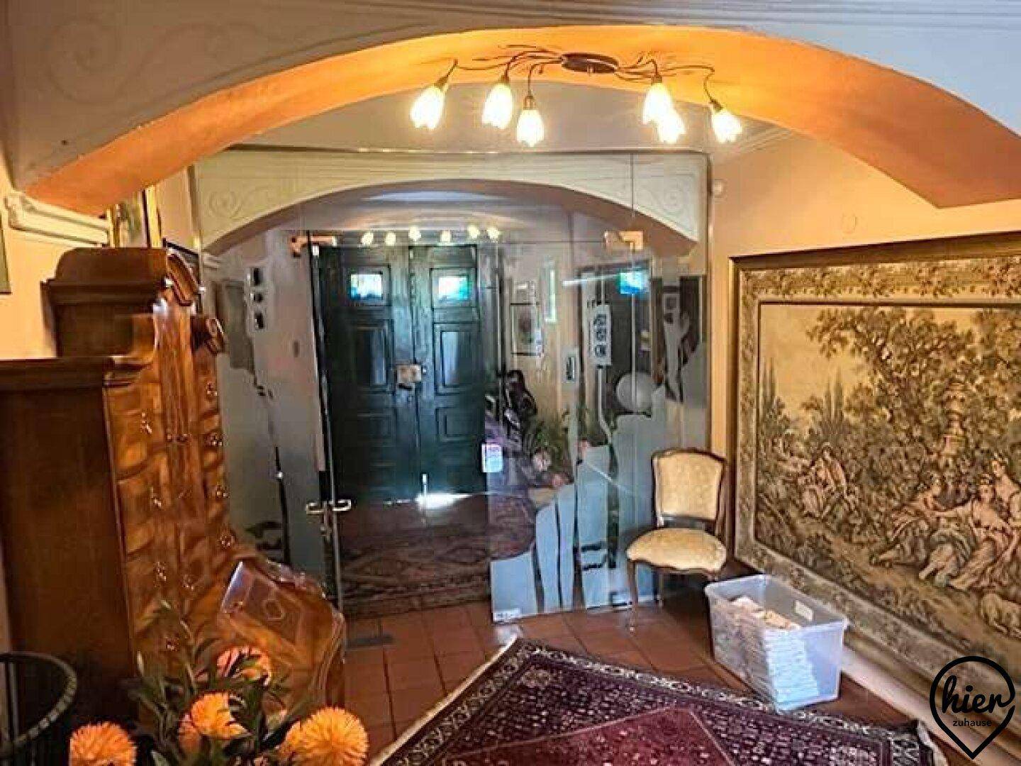 Eingangsbereich mit Glastüren, Fliesenboden und traditionellen Möbeln, die eine einladende Atmosphäre schaffen.
