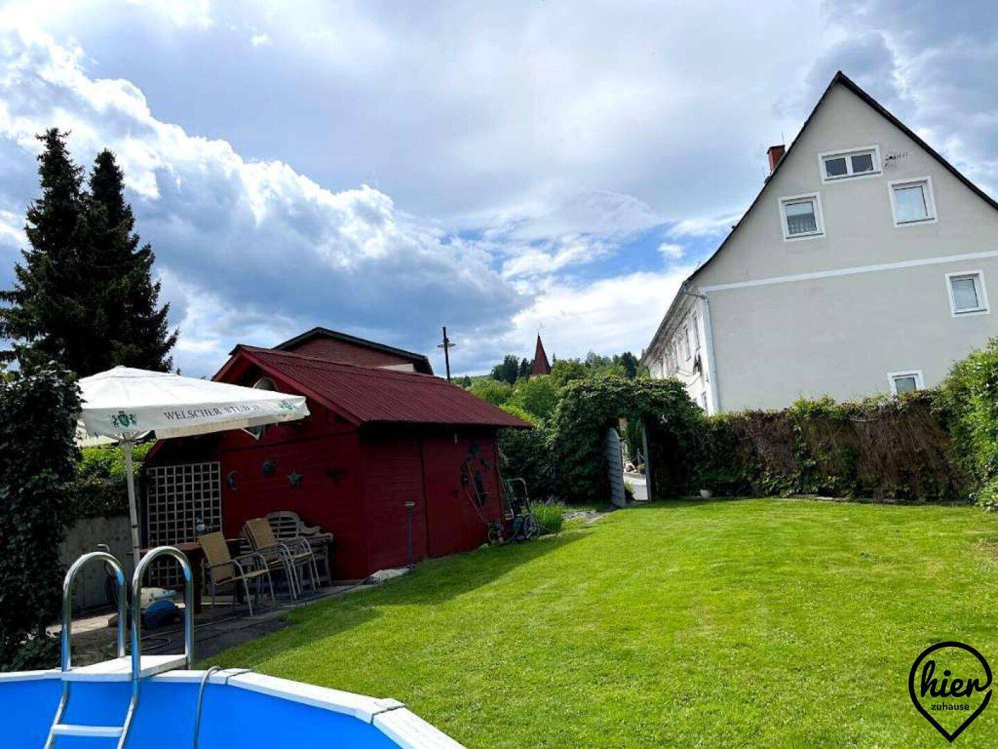Großer Garten mit Rasenfläche, einem roten Gartenhaus und einem Aufstellpool neben dem Wohnhaus.