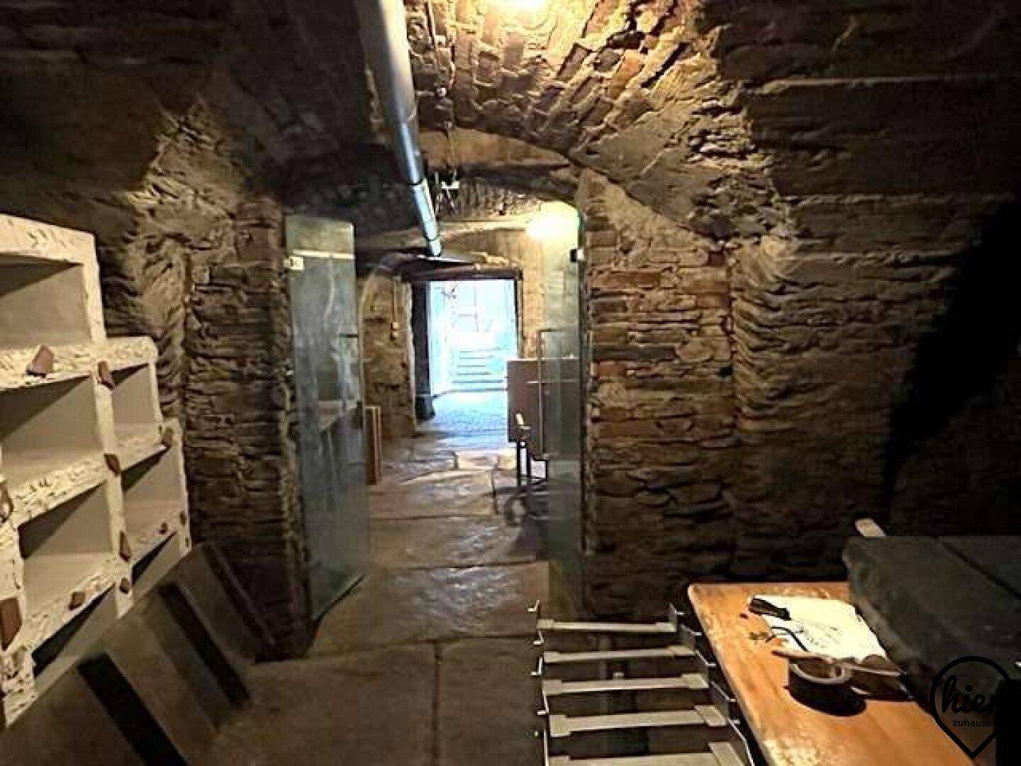 Ein historischer Gewölbekeller mit robusten Steinmauern und einem langen Gang, ideal für Lagerung.