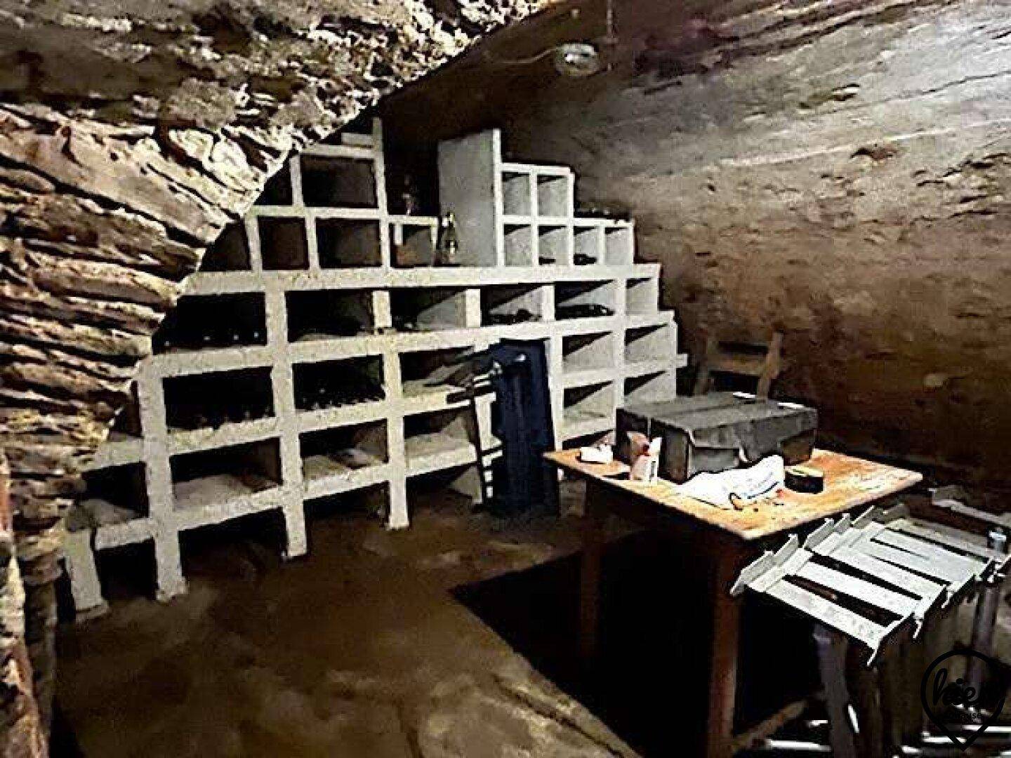 Ein traditioneller Weinkeller mit Steinmauern und eingebauten Regalen zur Lagerung von Weinflaschen.