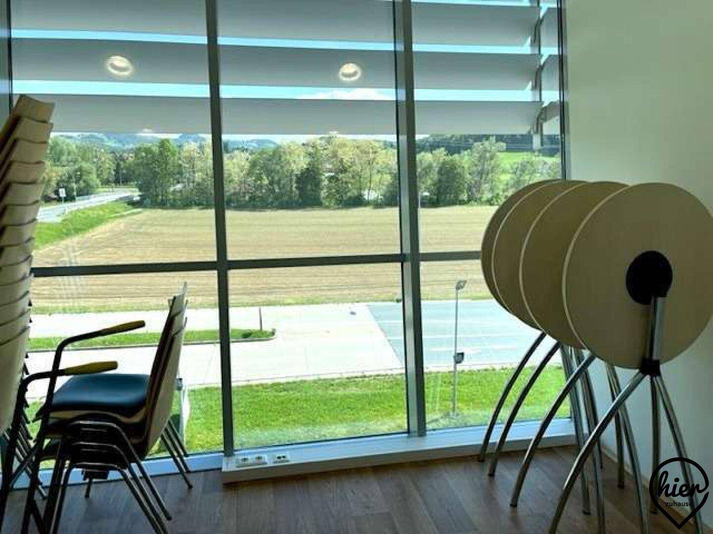 Lagerbereich für Stühle und Tische mit großen Fenstern und Blick auf die Landschaft.