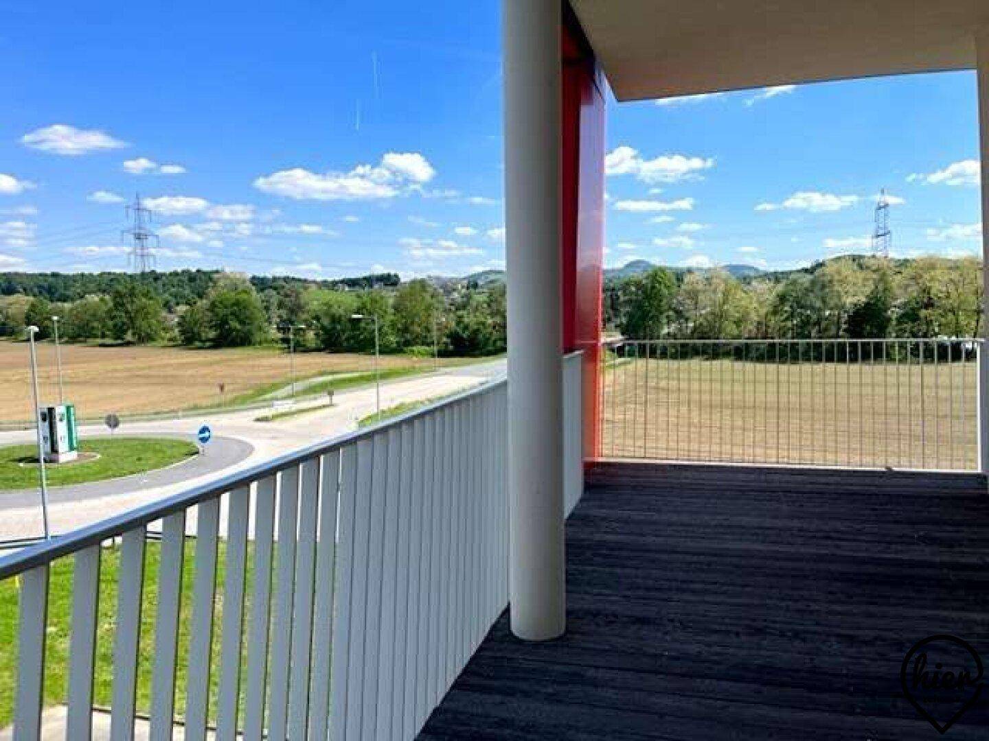 Geräumiger Balkon mit Holzboden und weitem Blick über Felder und die umliegende Landschaft.