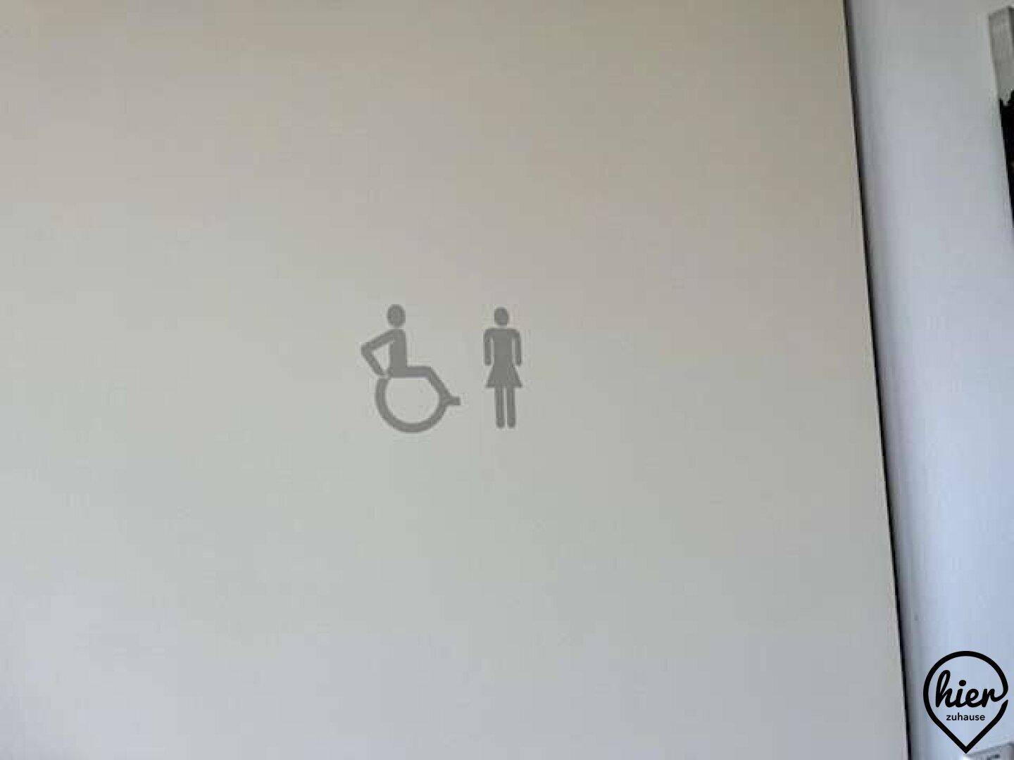 Weiße Tür mit Piktogrammen für Rollstuhlzugänglichkeit und Damen-WC.