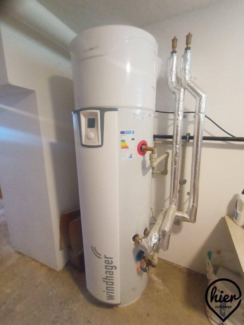 Moderner Warmwasserspeicher oder Wärmepumpe der Marke Windhager in einem Technikraum installiert.