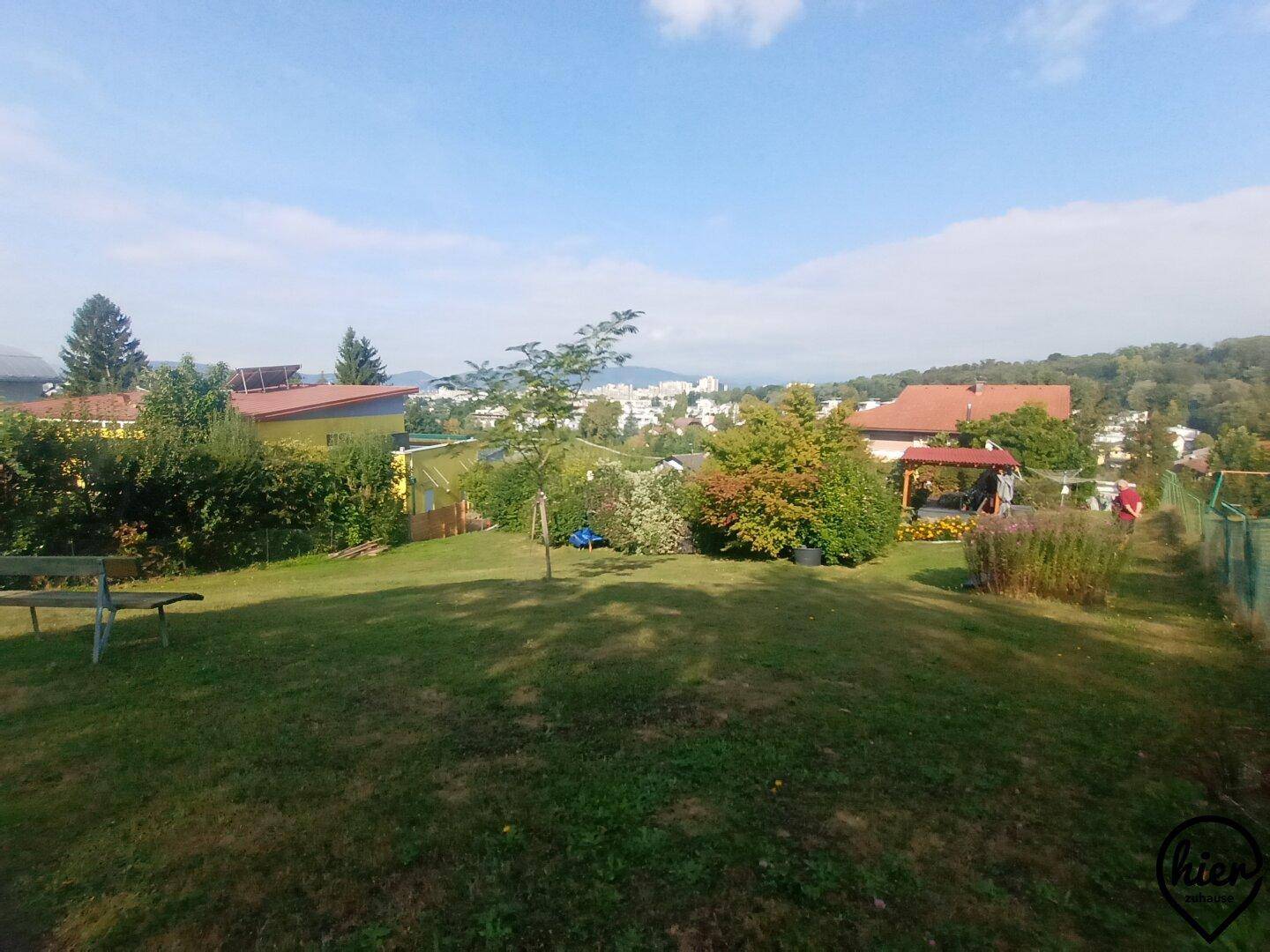 Weitläufiger, gepflegter Garten mit Rasenfläche, Bäumen und weitem Blick über die Umgebung.