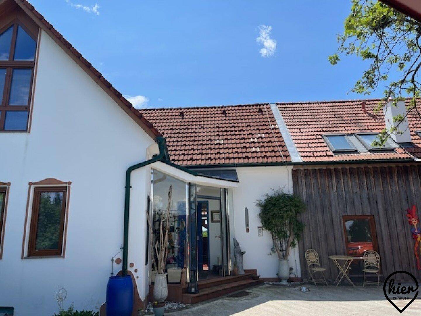 Charmantes Haus mit weißer Fassade, rotem Ziegeldach und modernem Glaseingangsbereich.