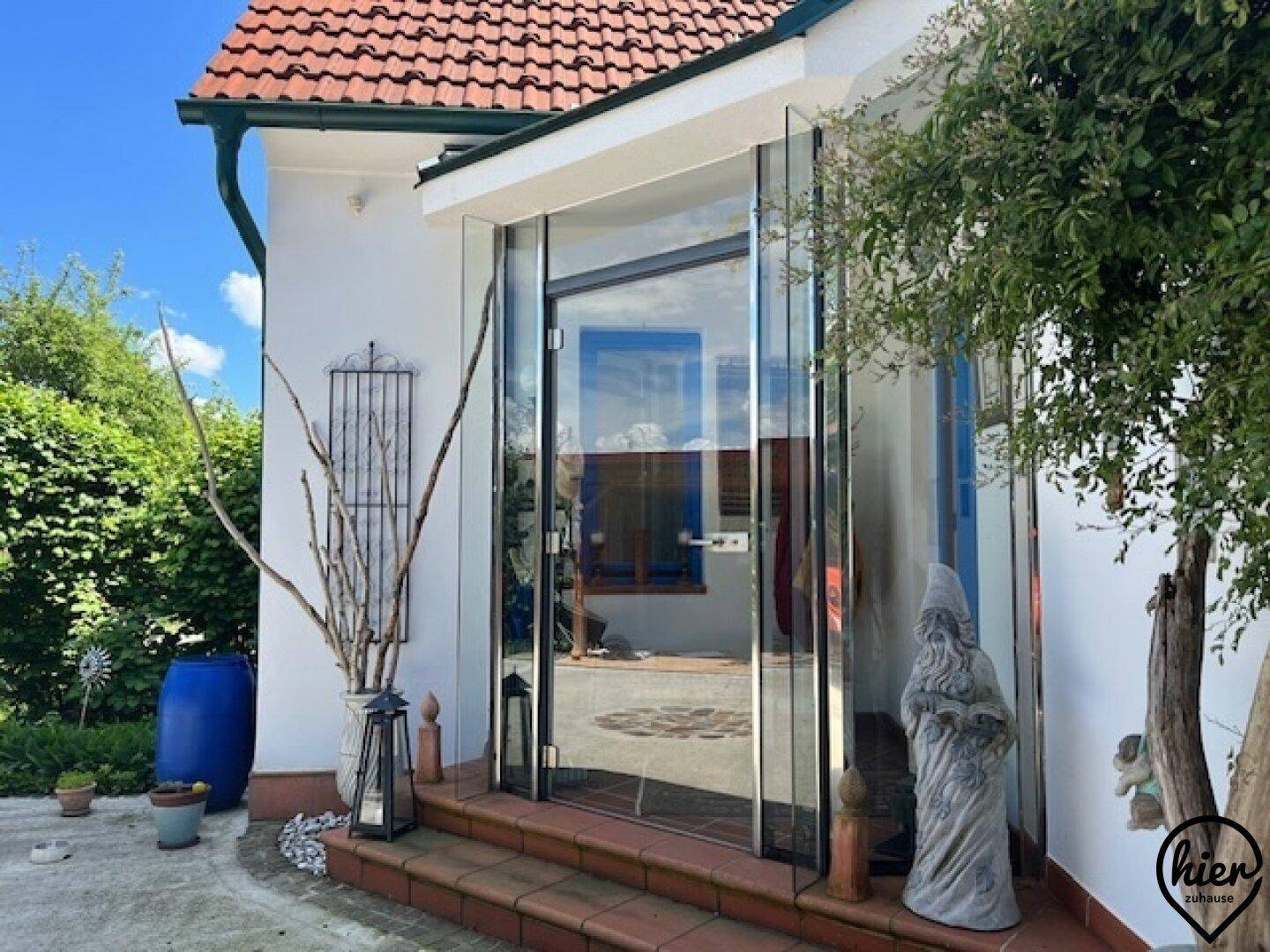 Heller Glaseingangsbereich des Hauses mit Stufen und dekorativen Elementen im Freien.