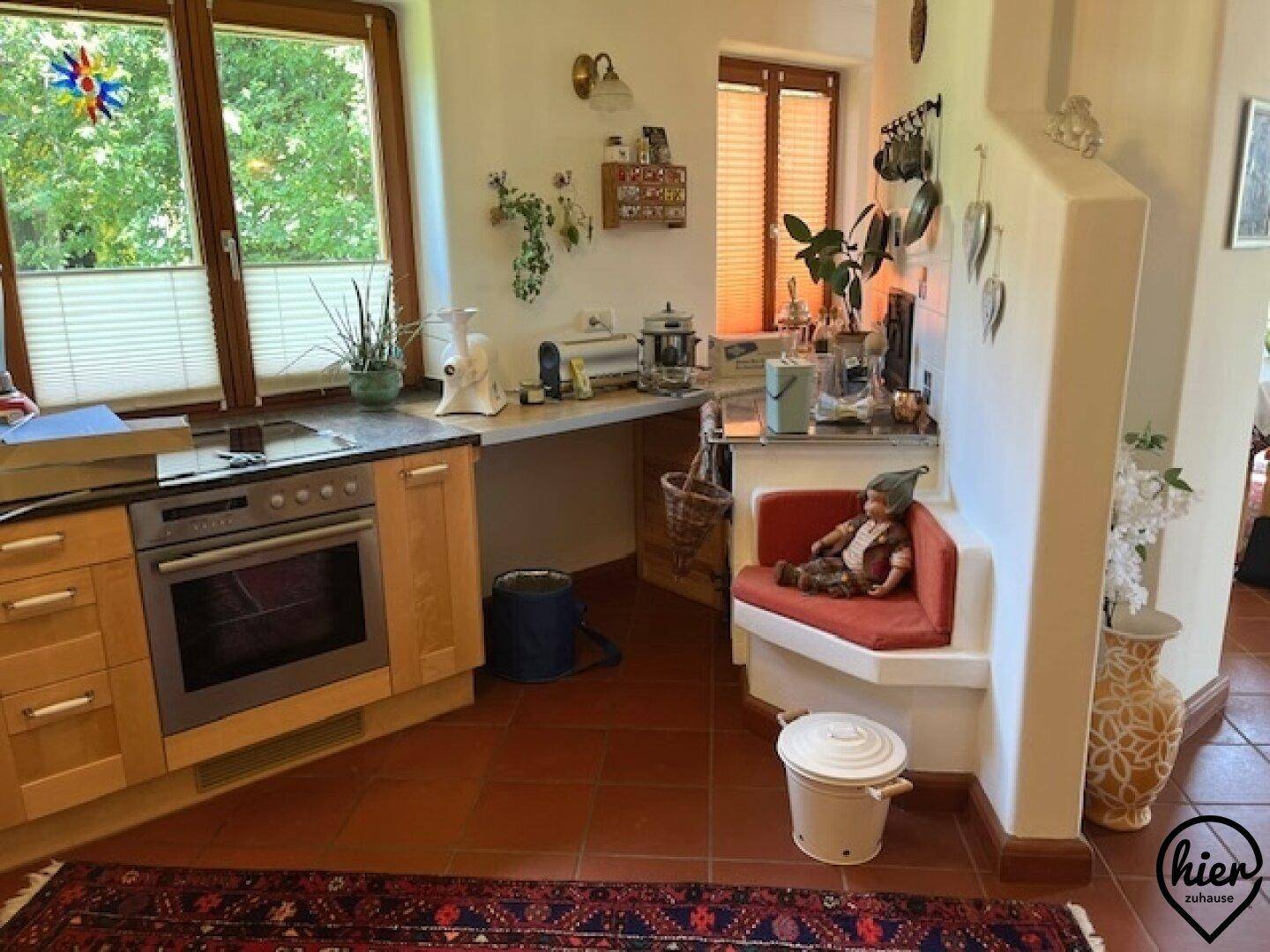 Funktionale Küche mit Backofen, Kochfeld und einer gemütlichen Sitzecke neben einem Kachelofen.