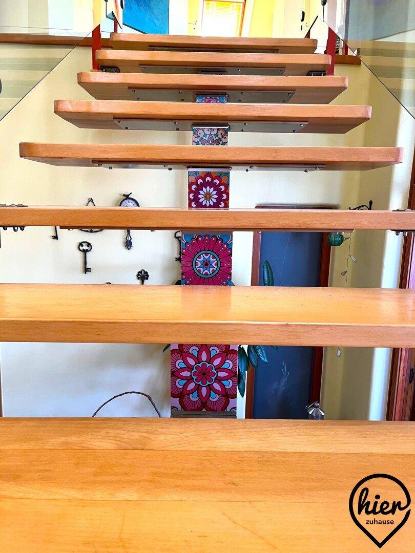 Holzstufen der Treppe mit farbenfrohen, dekorativen Fliesen an der Wand im Hintergrund.