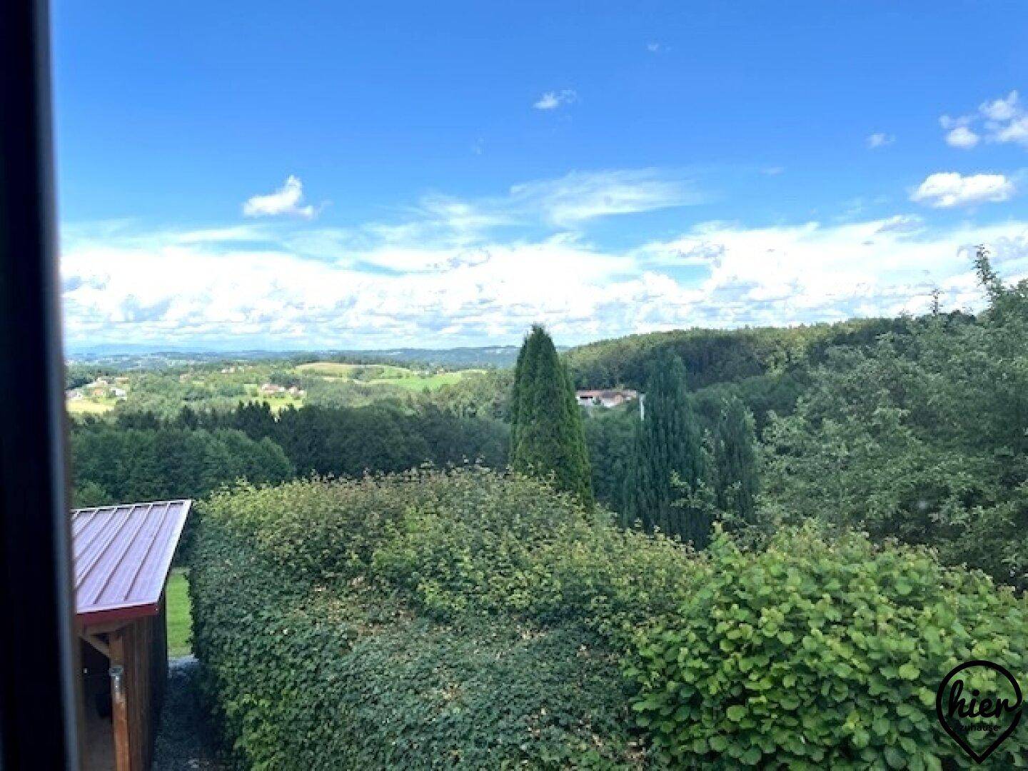 Malerischer Ausblick aus dem Fenster auf einen grünen Garten und die umliegende Landschaft.
