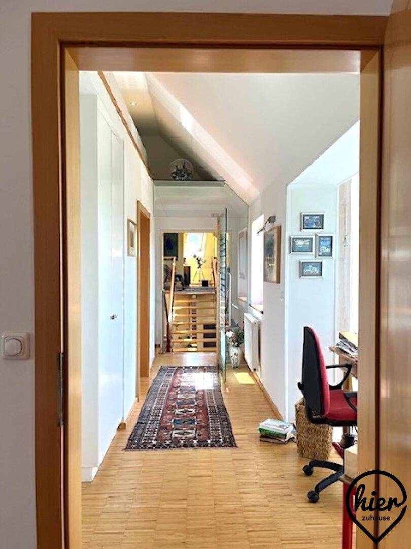 Heller Flur mit Holzfußboden, Teppich und einem Arbeitsbereich unter der Dachschräge.