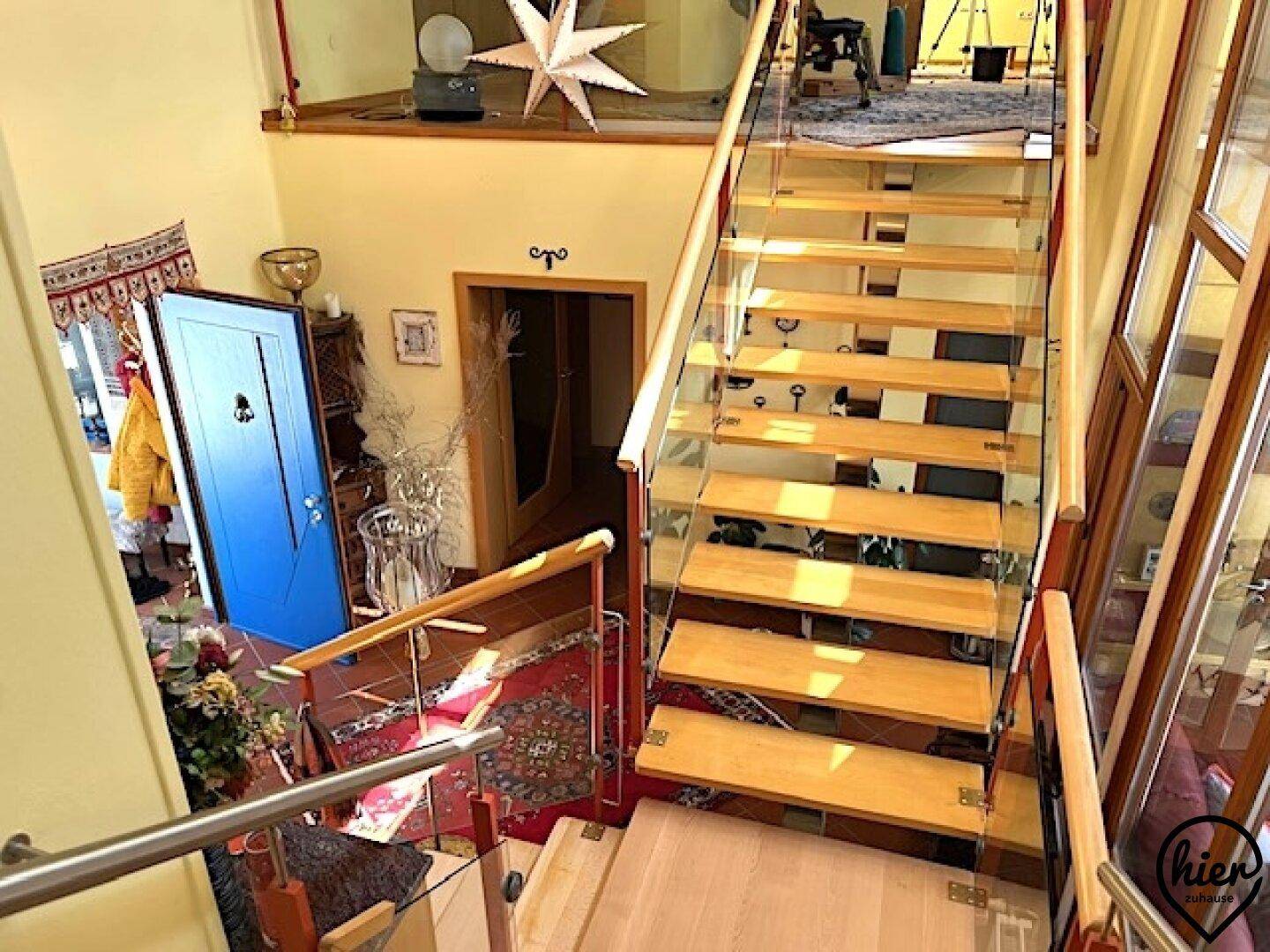 Elegante Holztreppe mit Glasgeländer führt zu den oberen Etagen des Hauses.