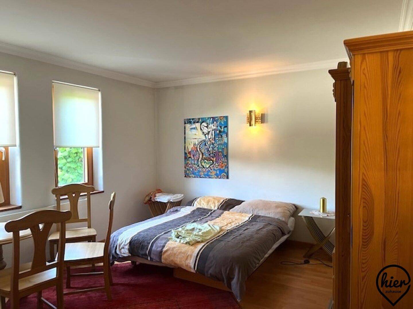 Gemütliches Schlafzimmer mit Doppelbett, Holzmöbeln und zwei Fenstern für natürliches Licht.