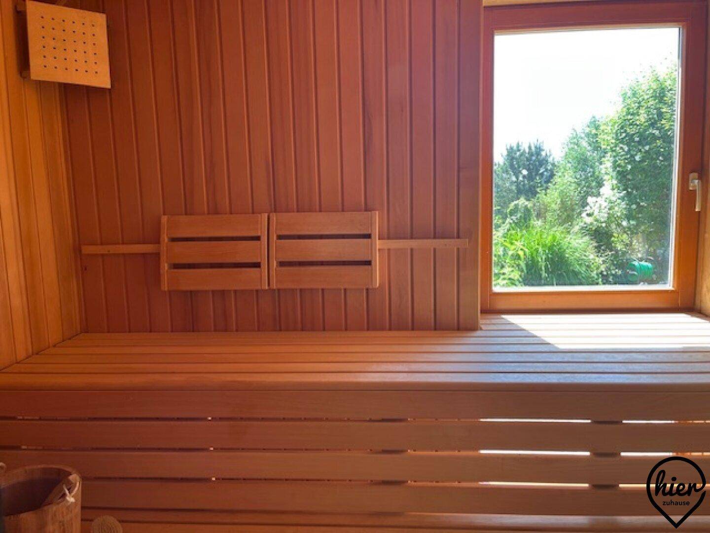 Helle Holzsauna mit Sitzbänken und einem Fenster mit Blick ins Grüne.