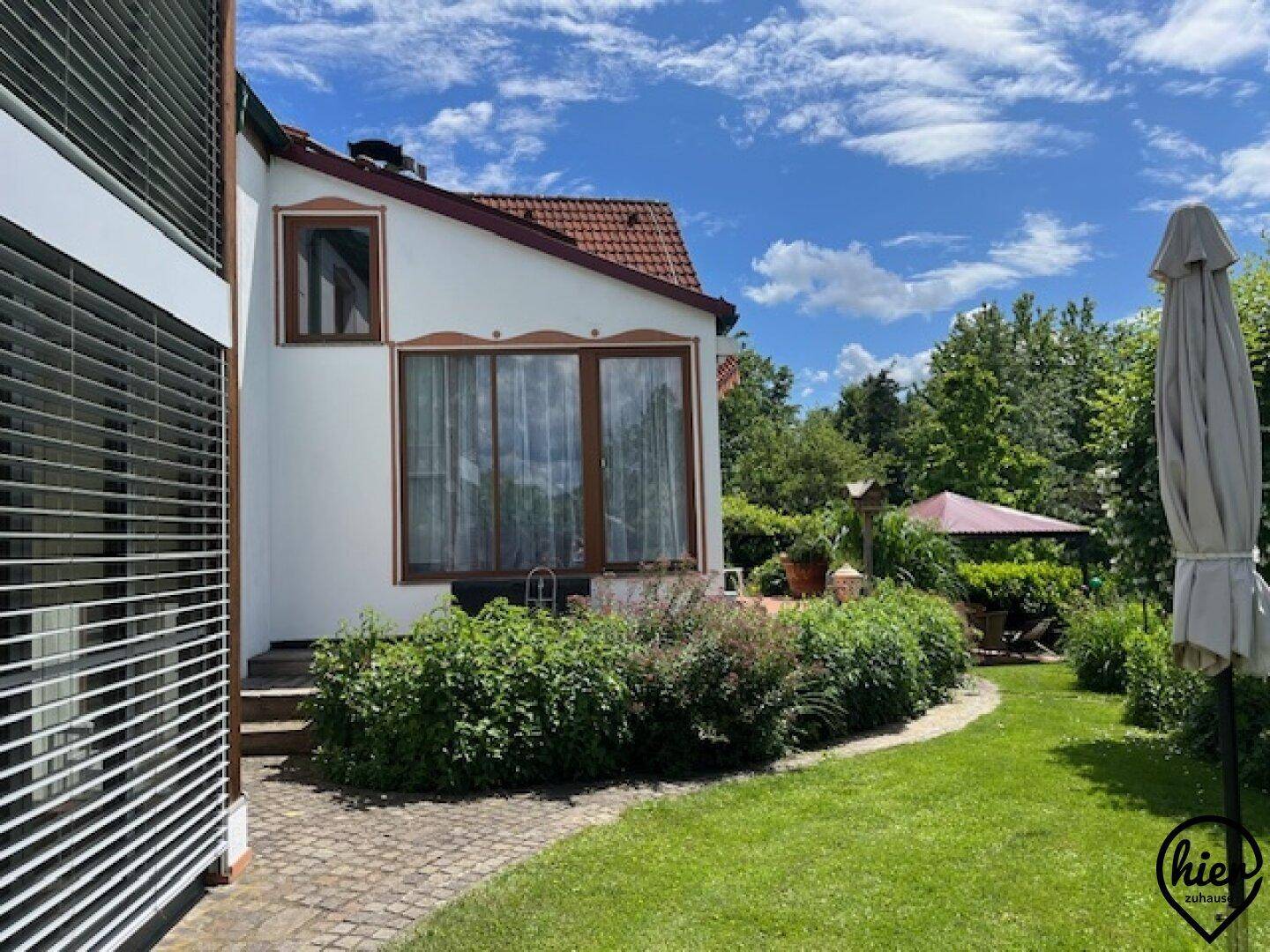 Gepflegter Gartenbereich mit Rasenfläche, Sträuchern und einem Weg neben dem Haus.