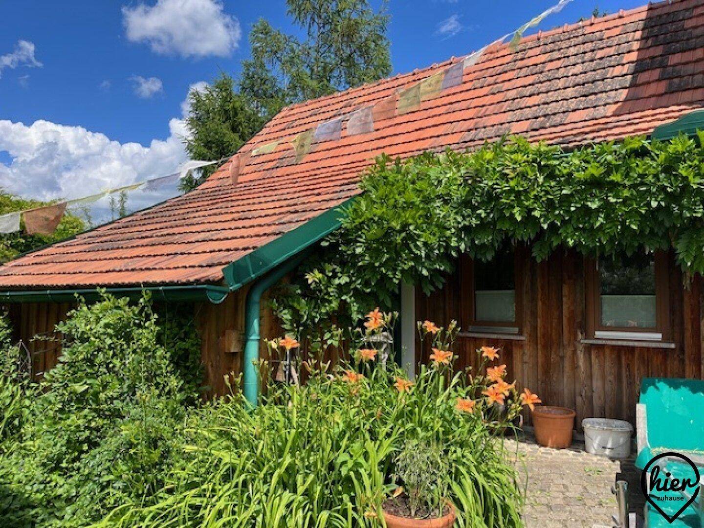 Charmantes Holzhaus mit Ziegeldach und blühenden Pflanzen im Vorgartenbereich.