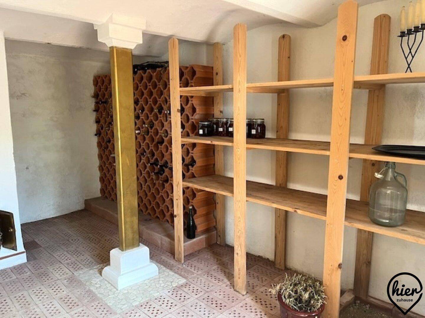 Rustikaler Weinkeller mit Holzregalen, Weinflaschen und gefliestem Boden.