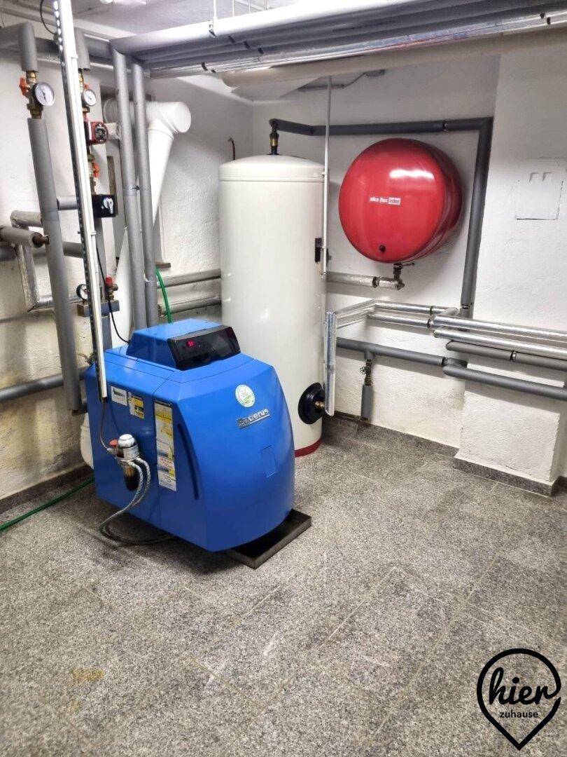 Technikraum mit Heizungsanlage, Warmwasserspeicher und zahlreichen Rohrleitungen.