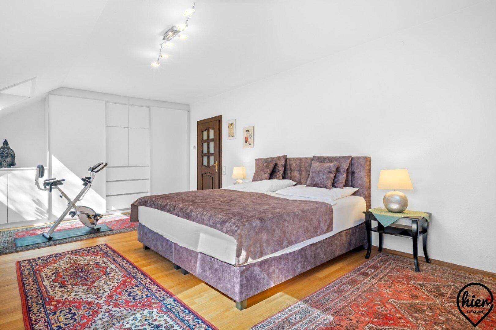 Geräumiges Schlafzimmer im Dachgeschoss mit Doppelbett, Einbauschränken und Holzboden, hell und funktional.