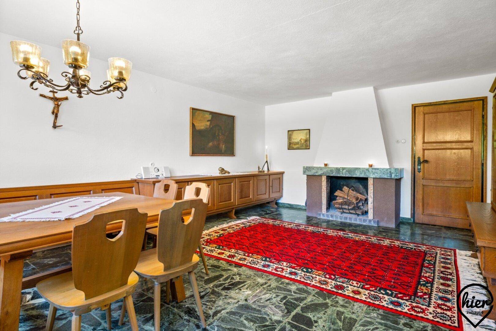 Traditioneller Essbereich mit Holztisch, Stühlen, Kamin und dunklem Steinboden.