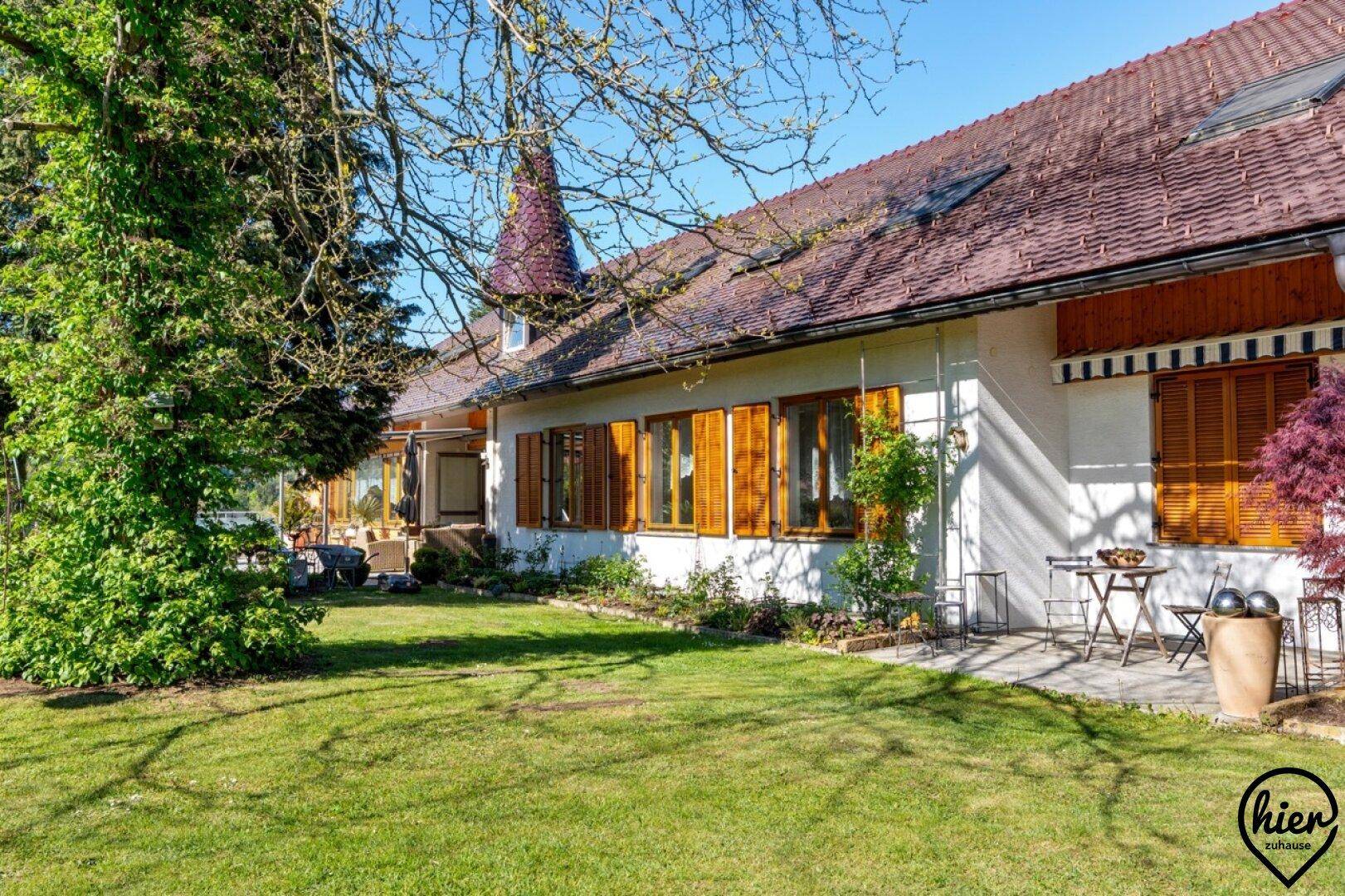 Großer Garten mit Rasenfläche, Bäumen und einer Terrasse am Haus.