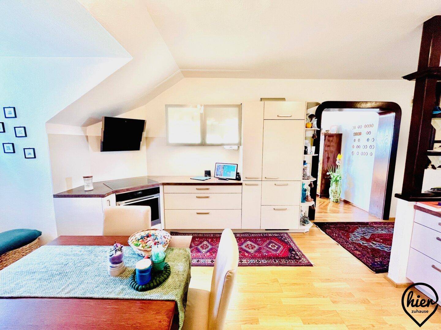 Moderne Einbauküche im Dachgeschoss mit hellen Fronten, integrierten Geräten und einem Essbereich, sehr praktisch.