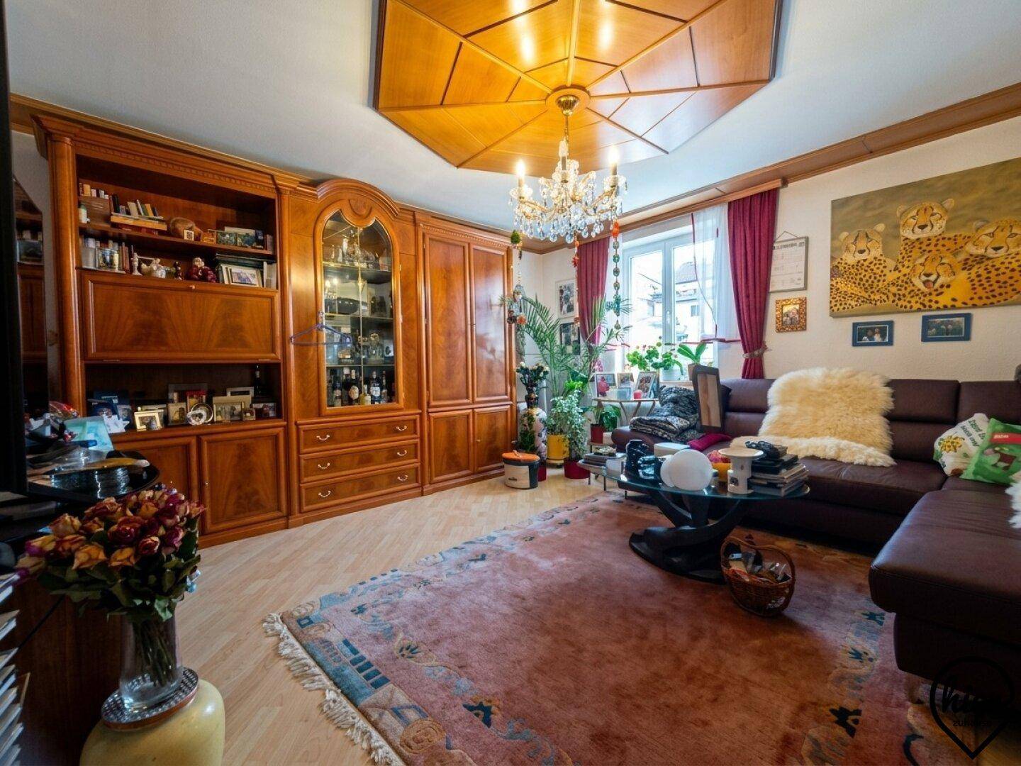 Traditionelles Wohnzimmer mit Holzboden, Kronleuchter und großem Holzschrank im klassischen Stil.