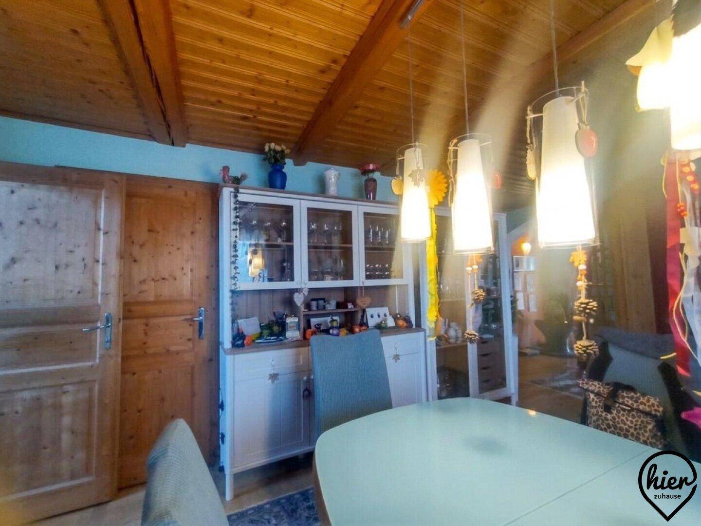 Gemütlicher Essbereich mit Holzbalkendecke, Vitrinenschrank und traditionellen Pendelleuchten.