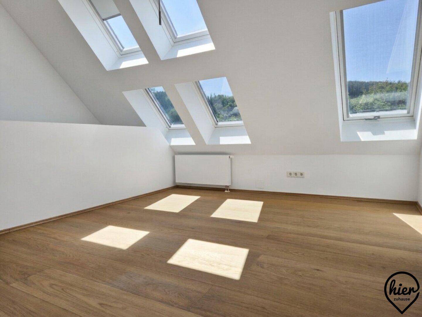 Helles Dachgeschosszimmer mit mehreren Dachfenstern, die viel Tageslicht hereinlassen.
