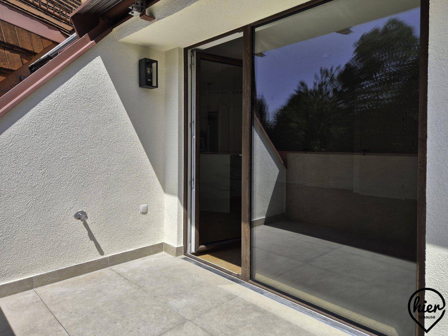 Heller Balkon mit Fliesenboden und Schiebetür, bietet einen ruhigen Außenbereich.