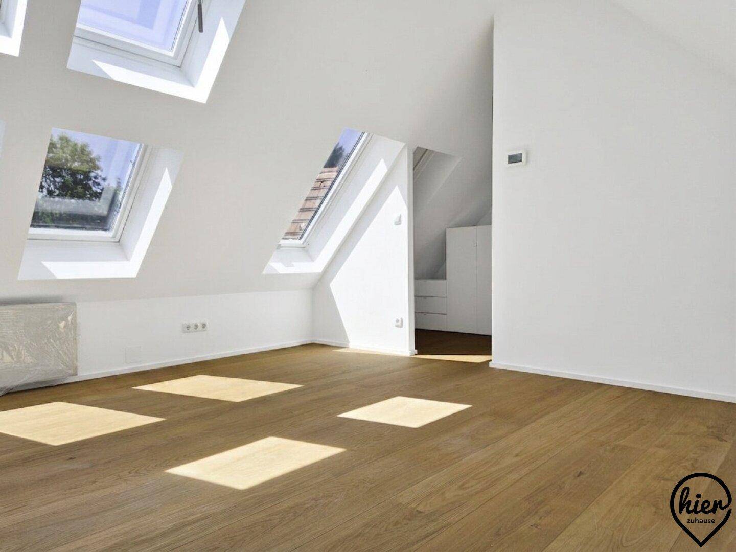 Lichtdurchflutetes Dachgeschoss mit Holzboden und praktischen Einbauschränken im Hintergrund.