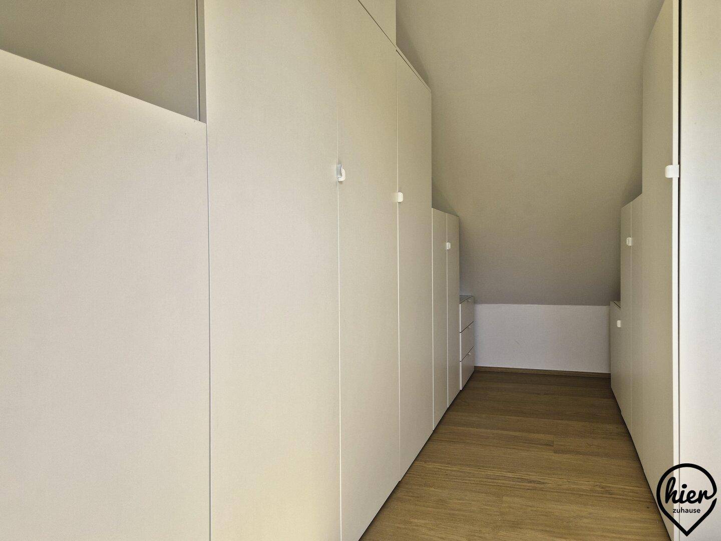Praktischer begehbarer Kleiderschrank mit vielen Einbauschränken und Holzboden.