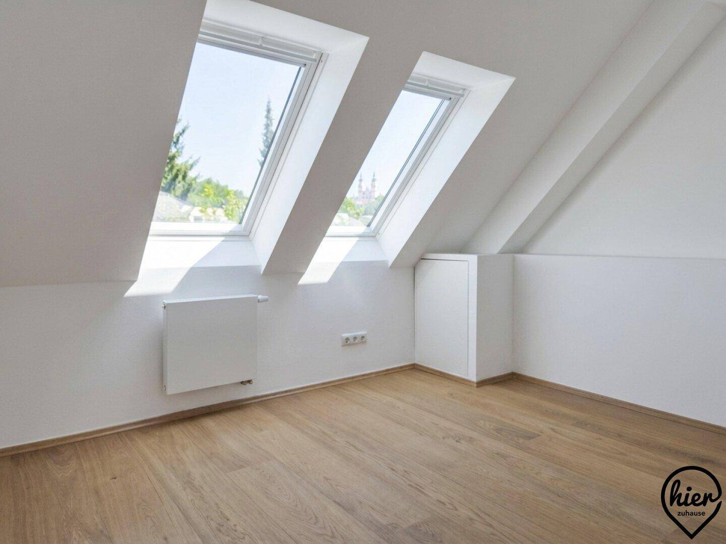 Dachgeschosszimmer mit zwei großen Dachfenstern, die einen weiten Blick ermöglichen.