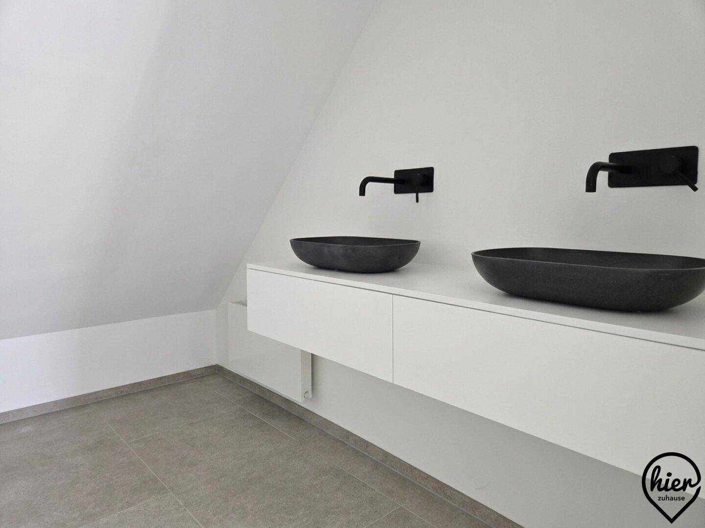 Modernes Badezimmer mit zwei Aufsatzwaschbecken und schwarzen Armaturen auf schwebendem Waschtisch.