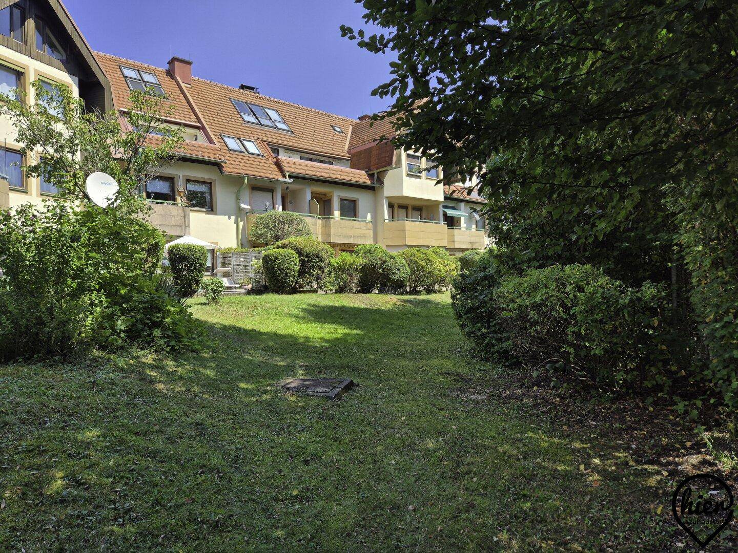 Gepflegter Gemeinschaftsgarten mit Rasenfläche und Hecken vor dem Wohngebäude.