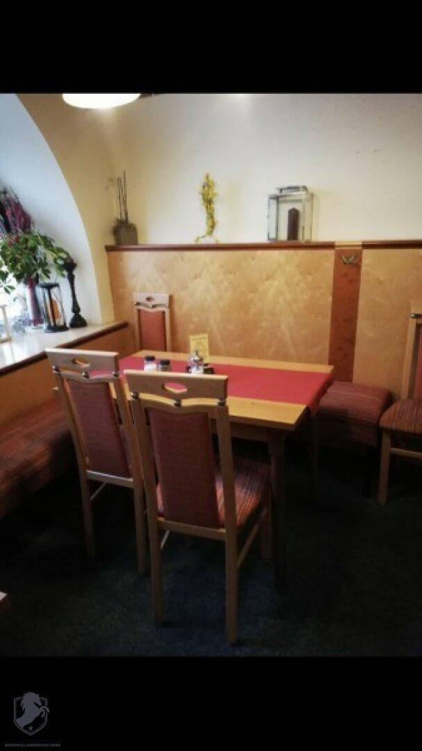 Einladender Speisesaal mit Holztischen, gepolsterten Bänken und traditioneller Wandgestaltung.