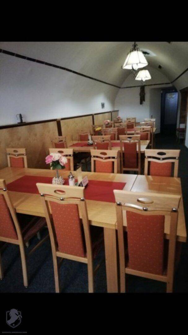 Gemütlicher Speisesaal mit Holztischen, roten Stühlen und einer markanten gewölbten Decke.