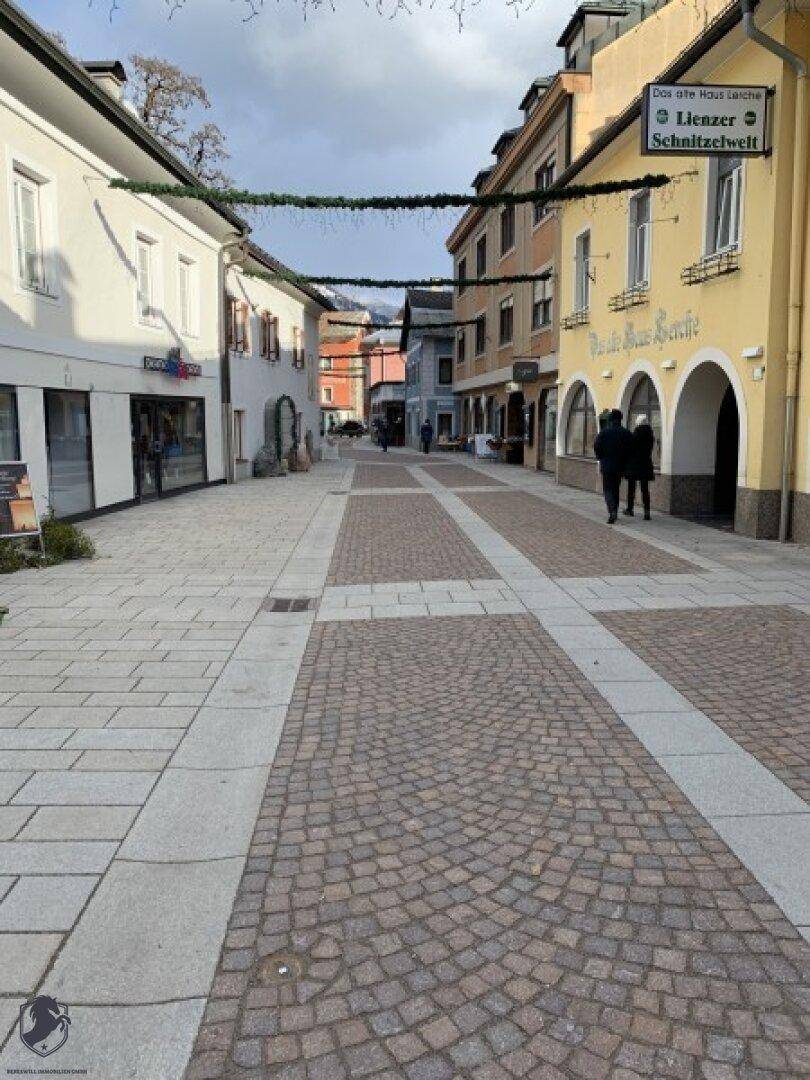 Historische Gebäude säumen eine gepflasterte Straße mit Blick auf die Berglandschaft.