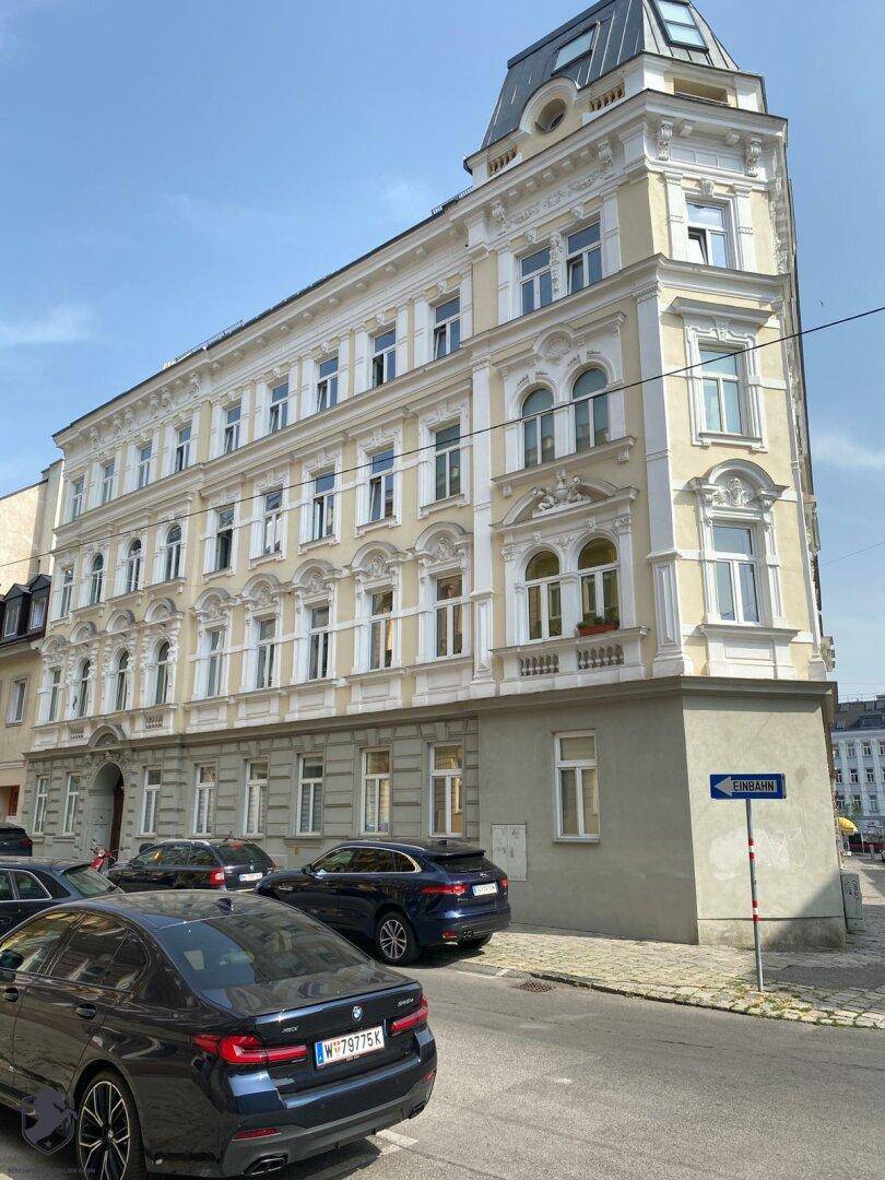 Seitenansicht des Altbaus mit klassischer Architektur und vielen Fenstern an einer städtischen Straße.