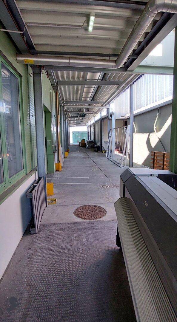 Überdachter Außenbereich oder Ladezone mit sichtbaren Rohren und Wellblechdach in industriellem Stil.