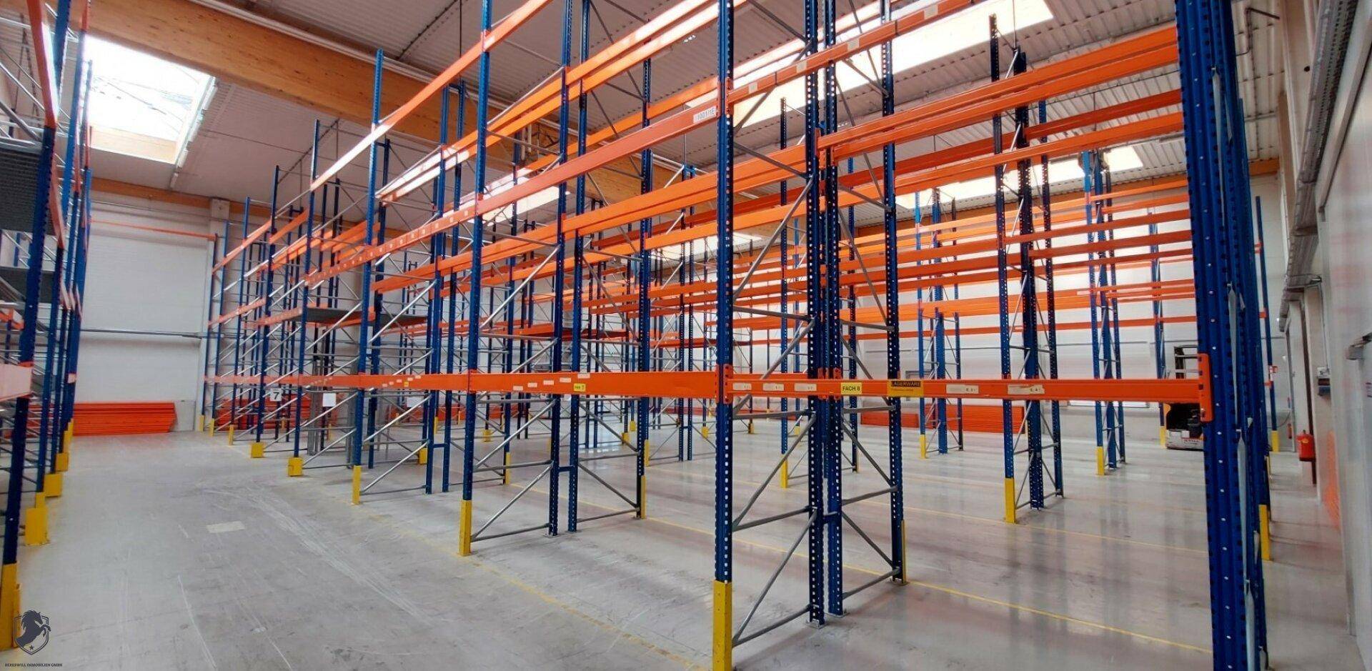 Leere Lagerhalle mit hohen Regalsystemen in Blau und Orange, bereit für die Bestückung.