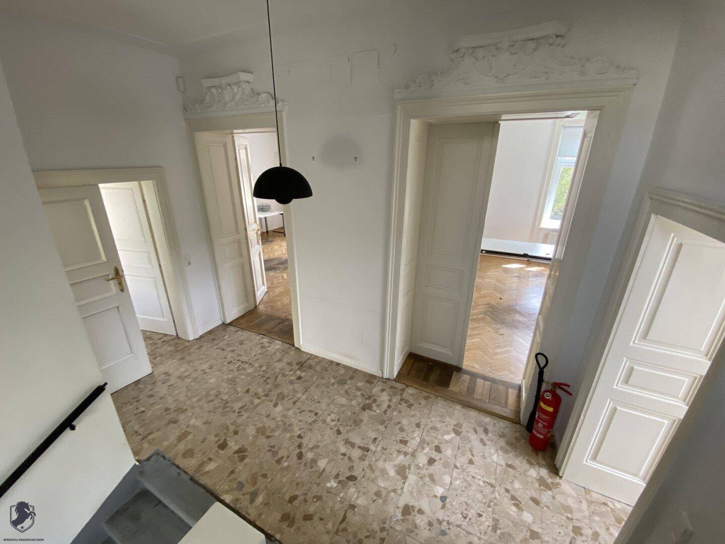 Heller Flur mit Terrazzoboden und hohen Türen, die zu weiteren Räumen führen.