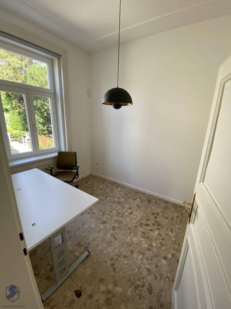 Kleiner Raum mit Terrazzoboden, Schreibtisch und Fenster, ideal als Arbeitszimmer.