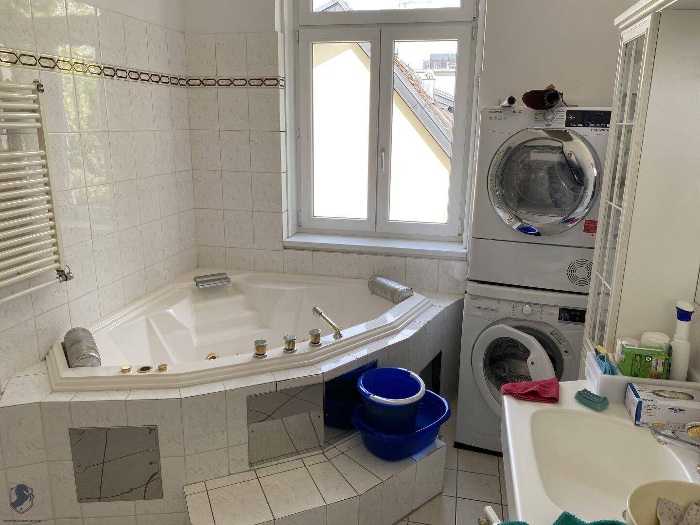 Badezimmer mit Eckbadewanne, Waschmaschine, Trockner und beheiztem Handtuchhalter.