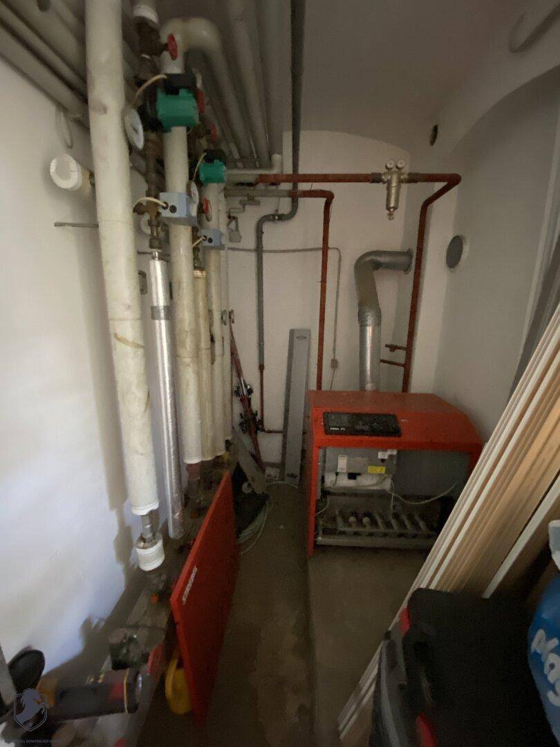 Heizungsraum mit Heizkessel, Rohren und technischen Installationen, dient als Versorgungsraum.